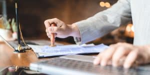 hand stamping with approved stamp on certificate document public paper at desk, notary or business